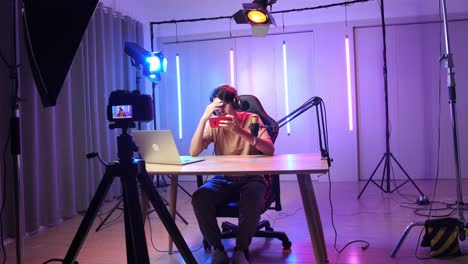 asian man playing video game with mobile phone then lose the game while live stream with camera, professional light equipment