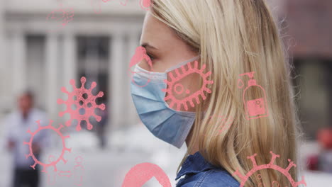 animation of virus cells and icons over caucasian woman wearing face mask