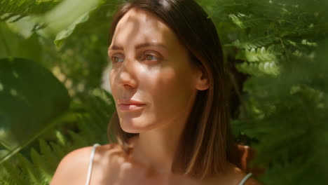 serene woman among green foliage with dappled sunlight