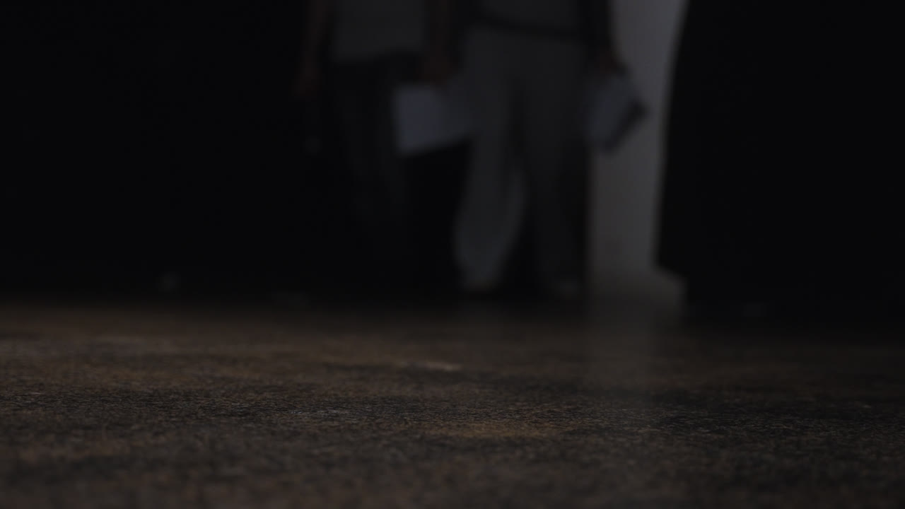 Beautiful slow motion close-up shot of the feet of a couple of actors arriving in a theater practice room to practice a scripted scene.