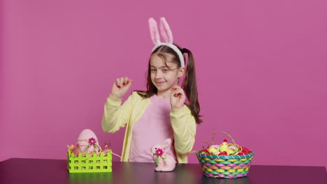 cheery innocent child showing peace sign in studio and wearing bunny ears