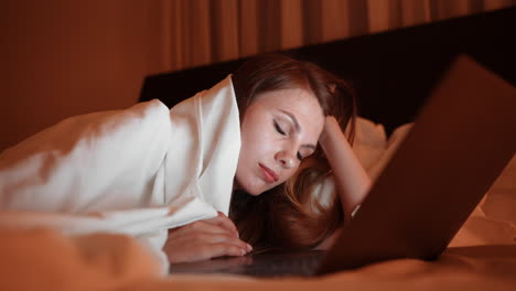 woman sleeping on laptop in bed at night