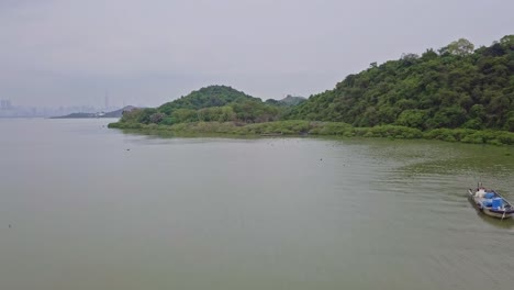 A-dynamic-onward-aerial-footage-of-the-peaceful-Lau-Fau-San-Island-with-2-fishing-boats-voyaging-the-calm-waters