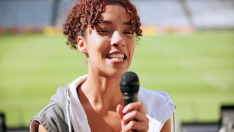 mujer cantando en un micrófono en un estadio deportivo