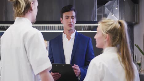 Mixed-race-male-restaurant-manager-in-the-kitchen-giving-instructions-to-Caucasian-cook
