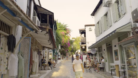 street in kas, turkey, with people shopping along narrow alleys surrounded by traditional stone buildings, static