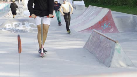 adolescentes montando scooters en un parque de patinaje