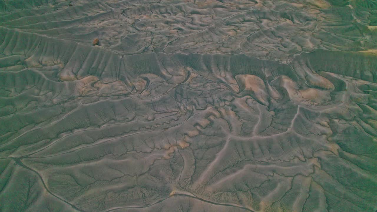 Drone view of Utah’s Factory Butte with rugged terrain, reosion patterns, striated slopes, sedimentary layers, and stark desert geology in 4k.