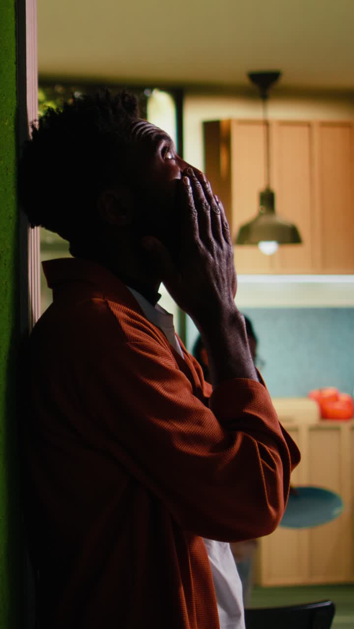 Vídeo vertical: Homem negro angustiado sente-se insatisfeito e decepcionado no corredor