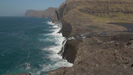 Vista-De-La-Cascada-Bosdalafossur-Con-Pila-De-Mar-Geitaskoradrangur-Al-Fondo-En-Las-Islas-Feroe