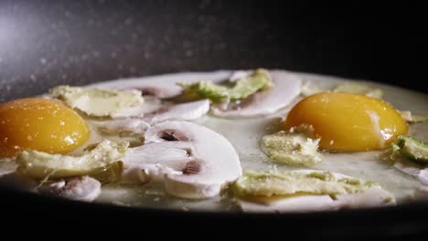 Salt,-Black-Pepper,-And-Cayenne-Pepper-Sprinkling-On-Eggs-With-Mushroom-And-Avocado-Cooking-In-A-Frying-Pan