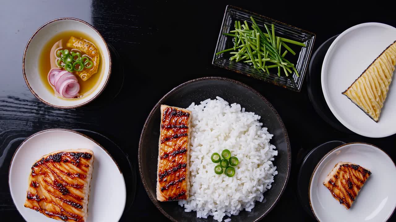 Top-down video shot of a Japanese meal with grilled fish, rice, and vegetables