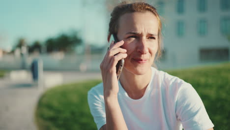 una mujer deportiva sonriente hablando por teléfono móvil al aire libre.
