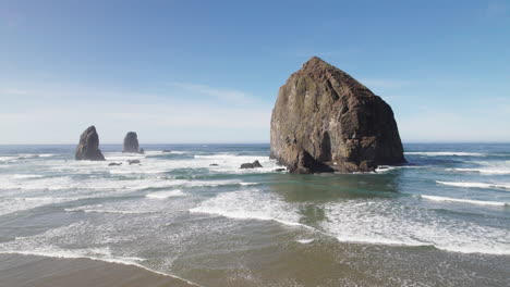 haystack rock looms over the waves at high tide