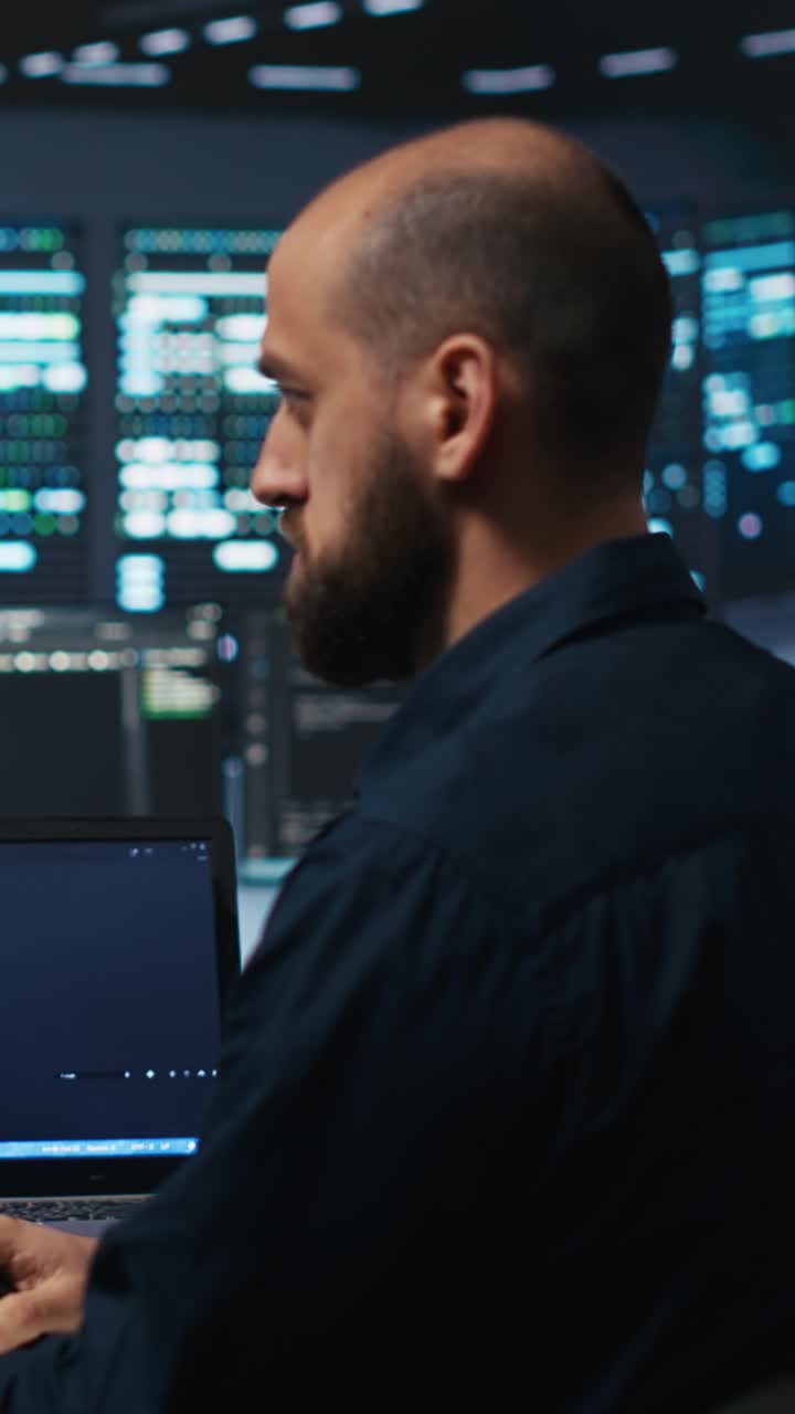 Focused Programmer Working on Laptop in Dark High-Tech Office
