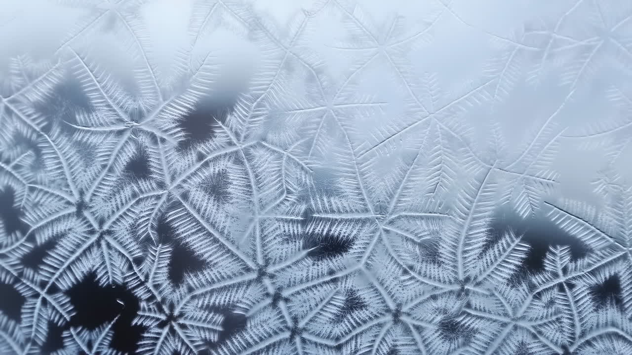 Primo piano di cristalli di brina sul vetro della finestra, delicati disegni di ghiaccio a forma di stella con simmetria esagonale, blu freddo