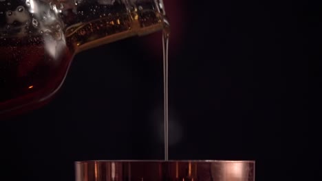 a bartender is pouring thick agave syrup into the copper boston shaker.