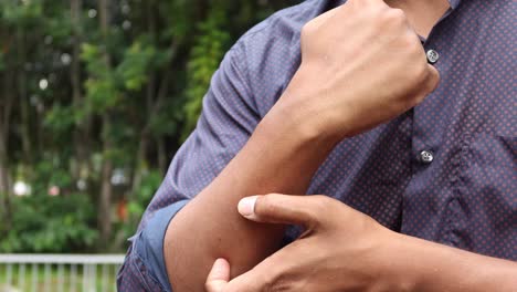 man scratching itchy wrist