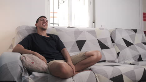 young man smiling and relaxing on sofa at home