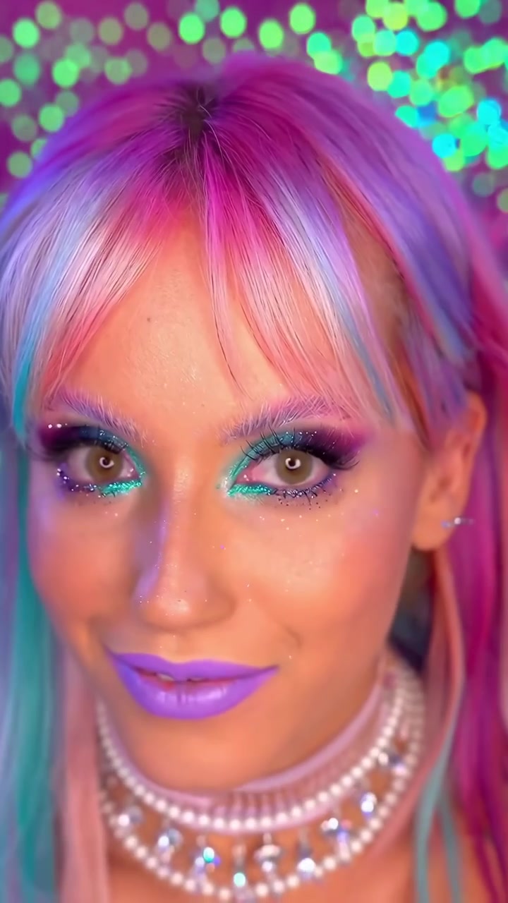 Giovane donna con capelli colorati e trucco glitterato in posa
