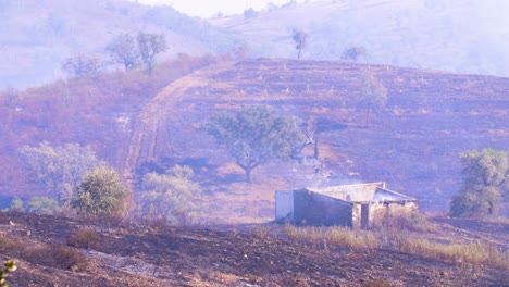 A-still-smoldering,-completely-burned-out-house-after-a-wildfire-in-the-mountains