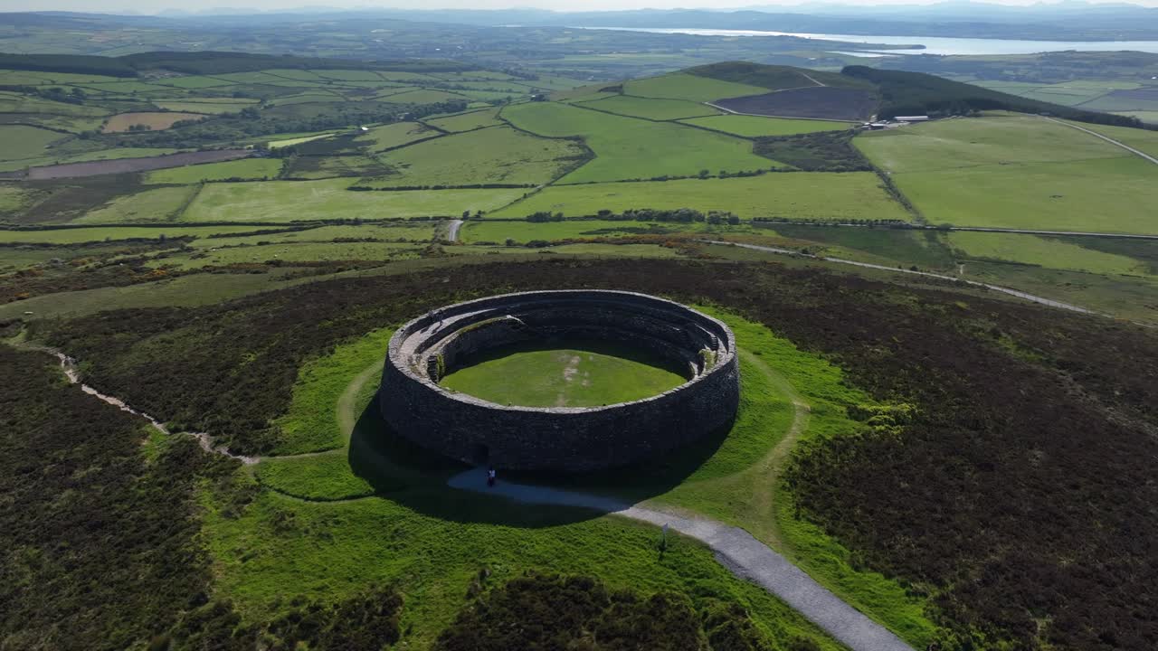 Grianan of Aileach, County Donegal, Ireland, June 2023. Drone counter clockwise orbit to close-up as people explore the historic Greenan Stone Fort with Lough Swilly in the distance.