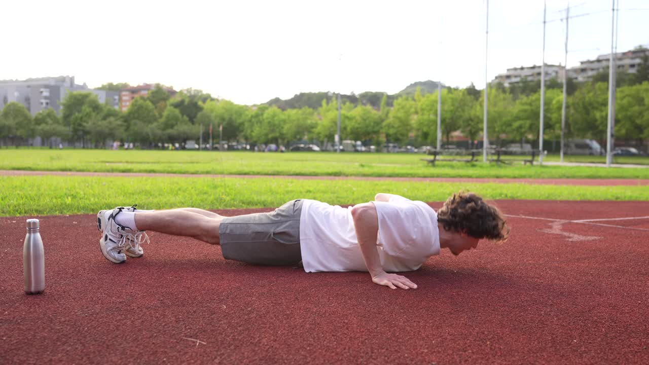 Man doing push-ups on a sports ground
