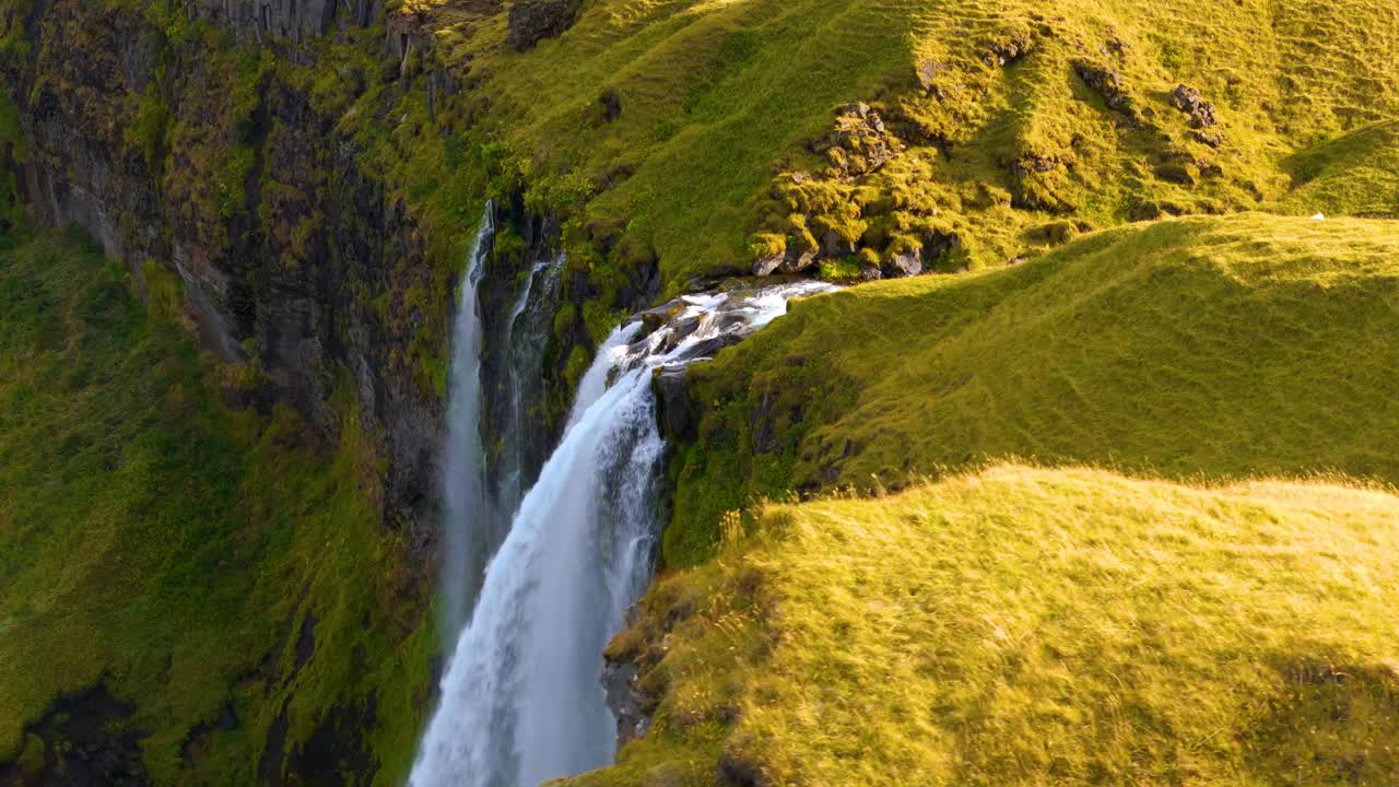 disparo en órbita lenta que revela la cascada de seljalandsfoss al atardecer