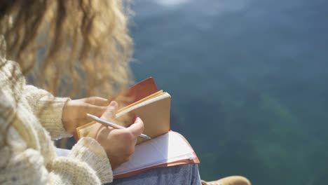 woman hipster writes in diary sitting on beach