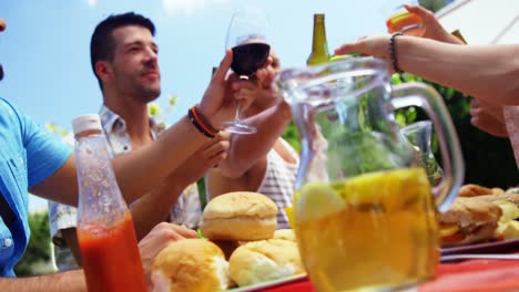 grupo de amigos felices brindando botellas de cerveza y vasos en una fiesta de barbacoa al aire libre