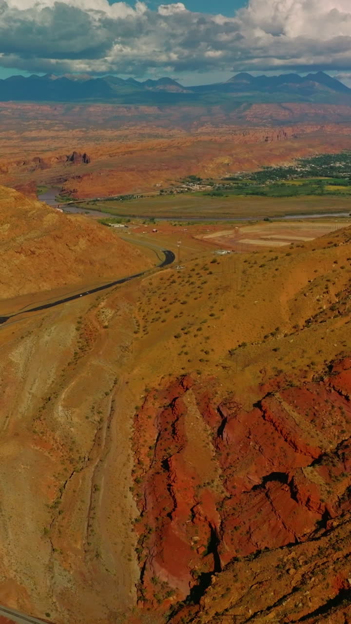 Rocks, deserts and green valleys in the national park of Utah. Drone flying over the motorway at the foot of canyon. Aerial perspective. Vertical video
