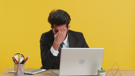 tired businessman rubbing his eyes at his desk