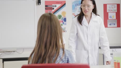 Diverse-female-teacher-and-girls-doing-experiments-in-elementary-school-chemistry-class,-slow-motion