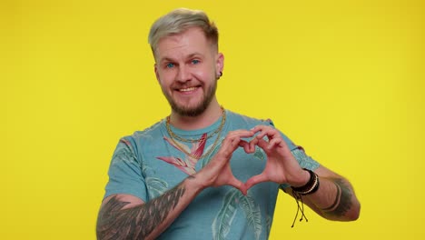 smiling tourist man makes heart gesture demonstrates love sign expresses good feelings and sympathy