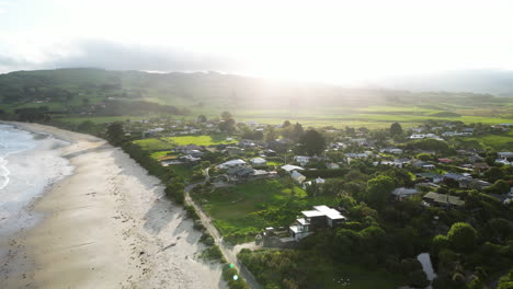 Vista-Aérea-De-Huriawa,-Comúnmente-Conocida-Como-Península-De-Huriawa-O-Península-De-Karitane,-Cálidas-Horas-Doradas-De-La-Puesta-De-Sol-Con-Pintorescas-Colinas-Verdes-Y-Costa