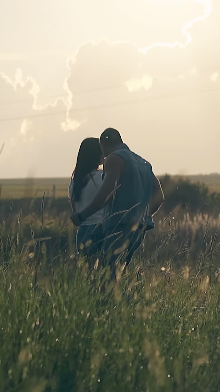 wonderful young couple dances on green endless meadow under orange cloudy sky at summer sunset slow motion