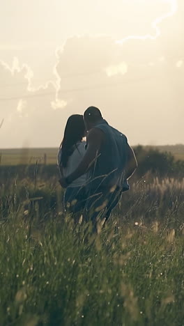 wonderful young couple dances on green endless meadow under orange cloudy sky at summer sunset slow motion