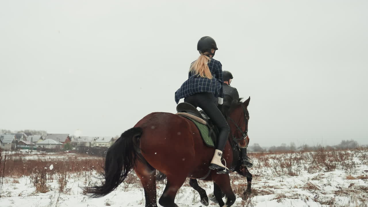 Due cavalieri cavalcano in tandem attraverso un prato innevato, partnership giocosa e tranquilla compagnia mentre la coppia naviga nel campo aperto, elmetti, movimento coordinato, sfondo rurale panoramico, calma stagionale e condivisa.