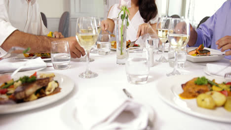 group of friends eating dinner together and toasting with wine