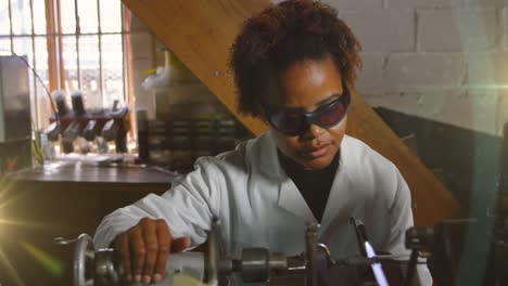 animation of glowing light over african american woman working in workshop