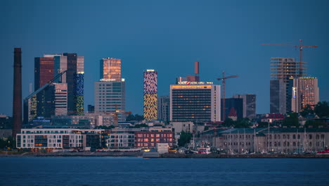 Dusk-to-moonrise-of-bright-yellow-moon-glowing-on-European-harbor-skyline