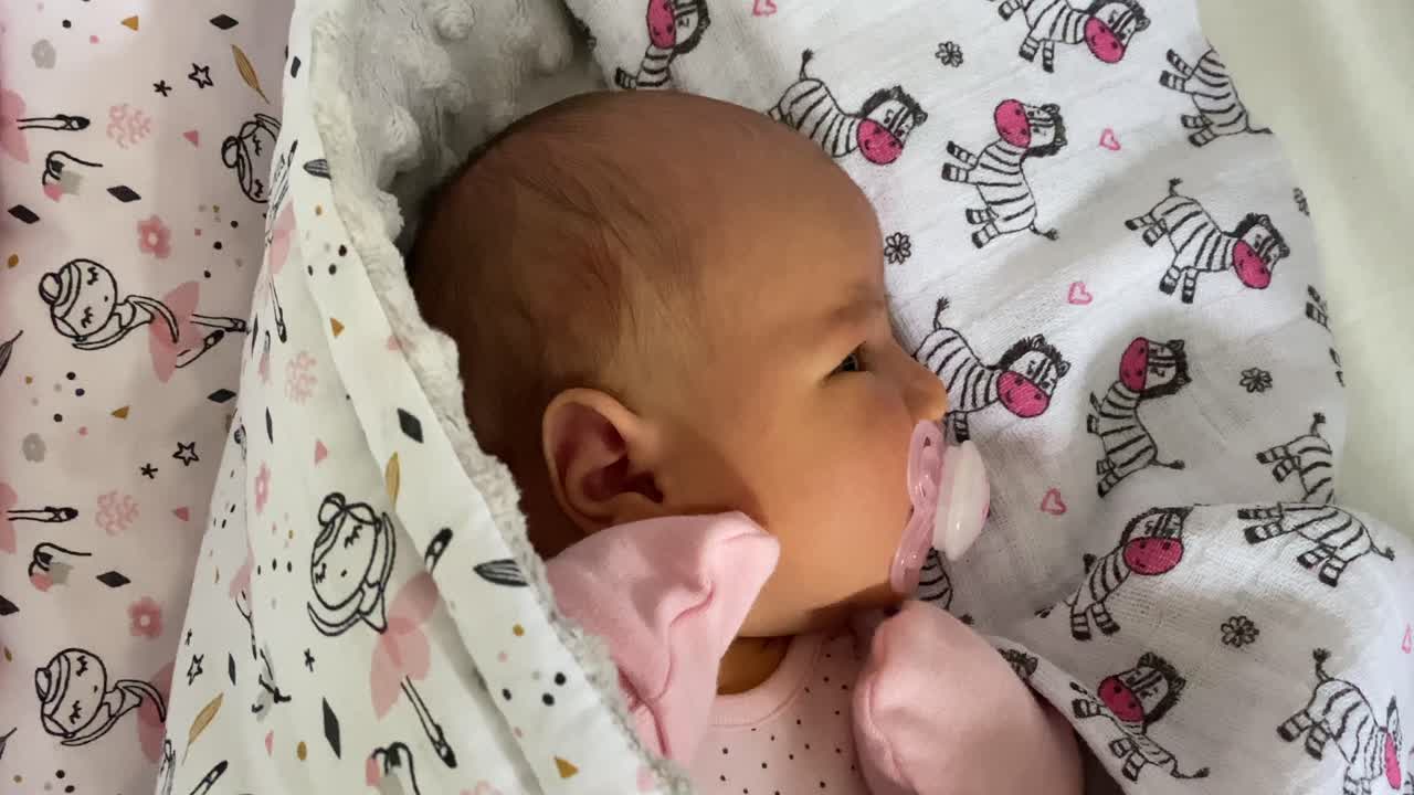 Una bambina che giace serenamente mentre succhia il ciuccio
