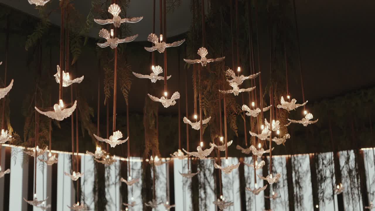 Colombe bianche decorative illuminate appese al soffitto che creano un'elegante atmosfera da matrimonio