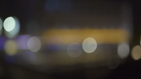 luces nocturnas desfocadas de la ciudad en el distrito comercial de parís. bokeh borroso de colores de los edificios. inclinación hacia arriba. 4k uhd.