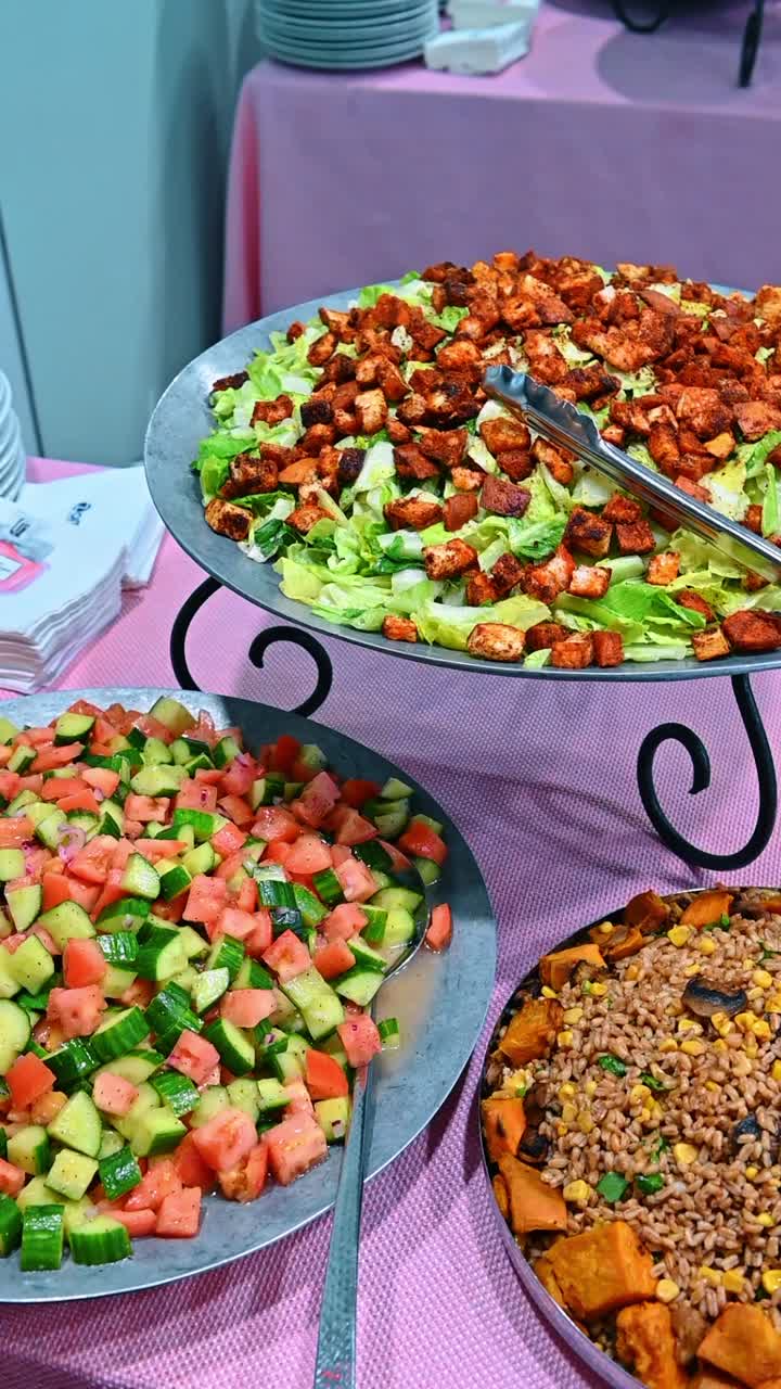 Assortimento a buffet di insalate fresche con crostini e verdure. Insalata Caesar con crostini, insalata di pomodoro e cetrioli e insalata di cereali con patata dolce su vassoi di servizio in metallo