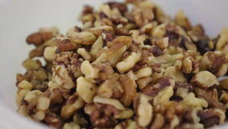 a white ceramic bowl full of peeled walnuts in close up