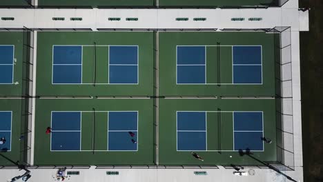 drone shot directly above people playing on four pickle-ball courts
