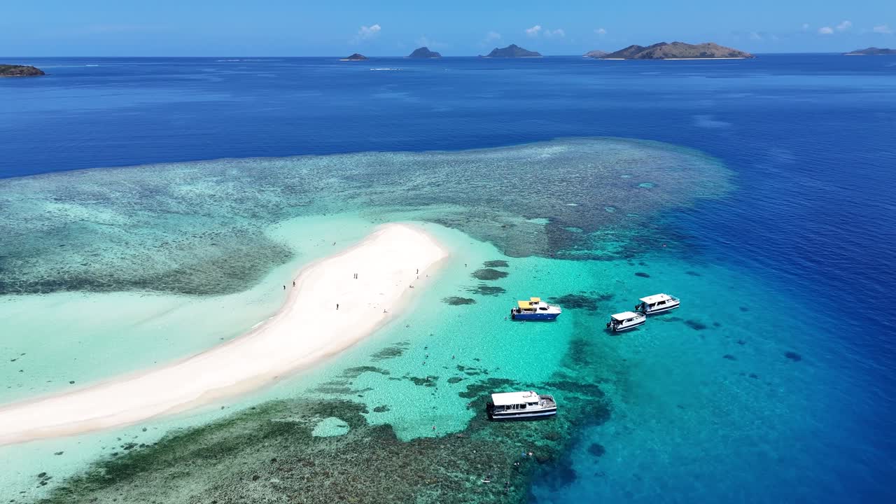 Breathtaking aerial drone view of a pristine white sandbar in the Mamanuca Islands, Fiji. tourist boat moored at bay