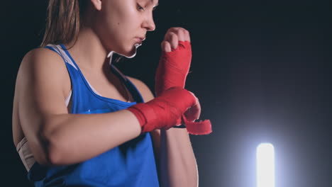 close-up of a beautiful athletic female boxer pulls red bandages on the hands of a female fighter. steadicam shot