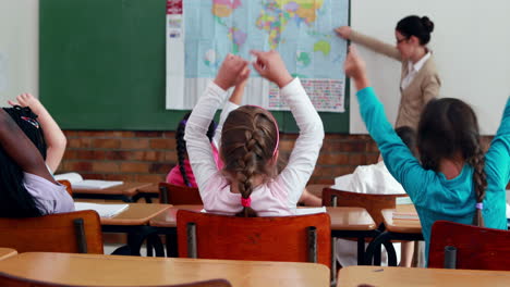 Niños-Pequeños-Escuchando-Al-Maestro-Mostrando-El-Mapa-En-El-Aula-